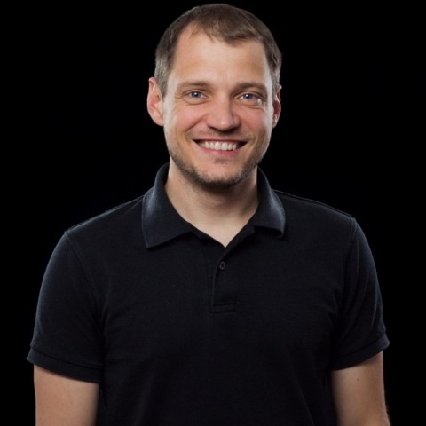 Wolfgang Kerler smiling into the camera dressed in black before black background