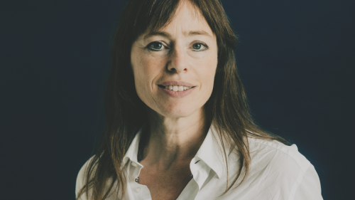 Hedwig Richter hat lange glatte Haare und trägt eine Bluse. Sie schaut in die Kamera und lächelt. Dabei steht sie vor einem dunklen Hintergrund.