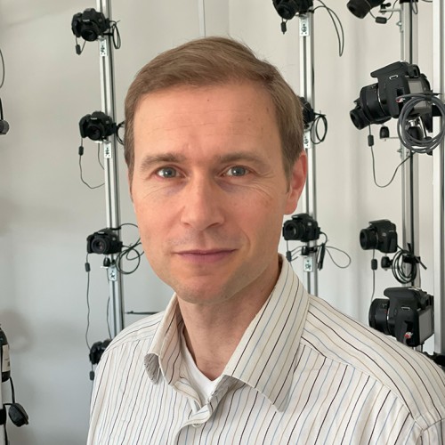 Portrait von Björn Stockleben, Brustbild mit einem Gerüst mit vielen Fotokameras im Hintergrund