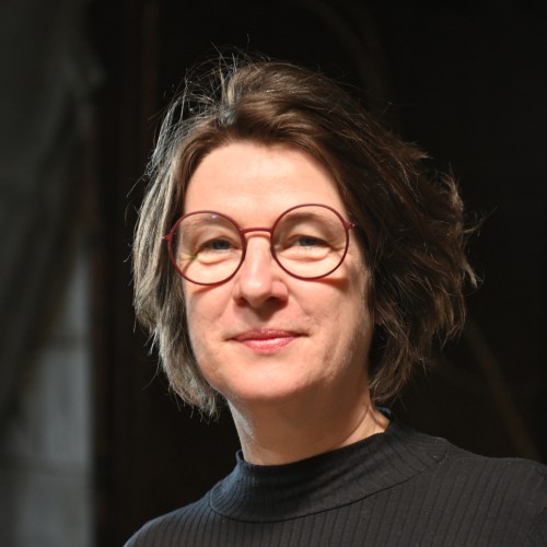 Jo Tiffe vor dunklem Hintergrund lächelnd in die Kamera blickend