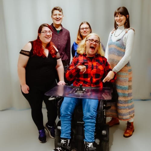 Fünf verschiedene Personen stehen zusammen und lächeln. Sie sind ein Team. Sie haben Spaß. 