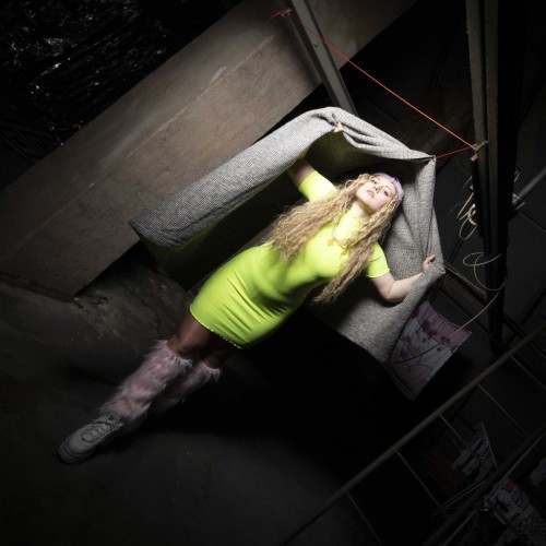 Foto der Künstlerin und Produzentin Aufmischen in grellgrünem Kleid und rosa Fellstulpen