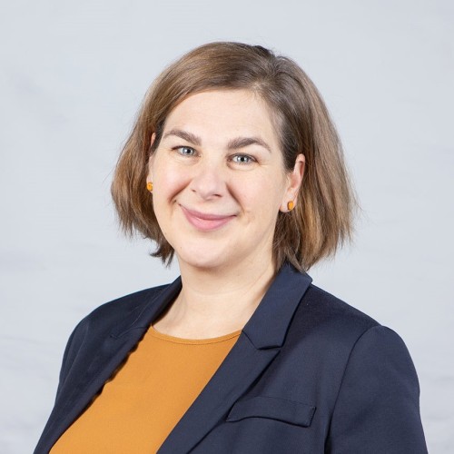 Annegret Prigge ist im Portrait zu sehen. Mit halblanger Frisur und braunen Haaren, lächelnd mit senffarbenen Oberteil und blauem Blaser.