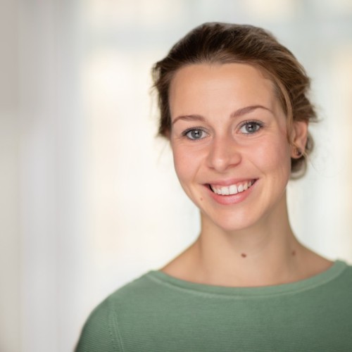 The image shows Anne-Marie Nussberger -- a woman with light brown hair tied back, wearing a light green top in front of a softly blurred background.