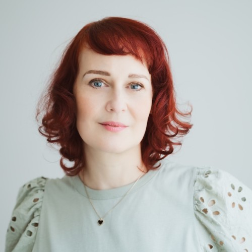 Eine sympatische Frau Ende Vierzig mit roten schulterlangen Haar die klar, mit einem leichten Lächeln in die Kamera schaut.