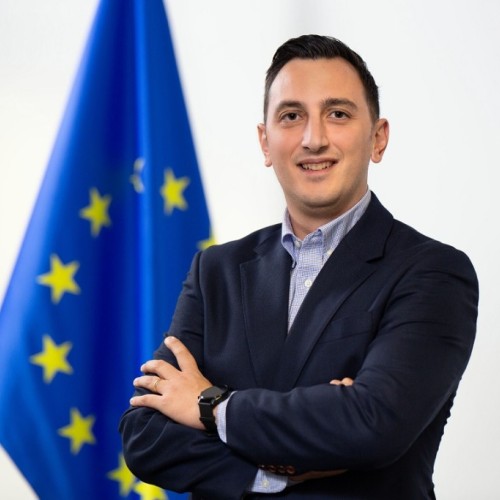 Glenn Micallef neben der Fahne der Europäischen Union