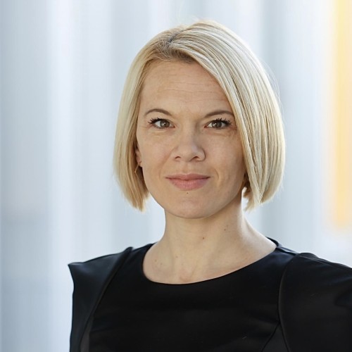 Laura Dornheim, leicht lächelnd, in schwarzem Oberteil vor unscharfem Hintergrund