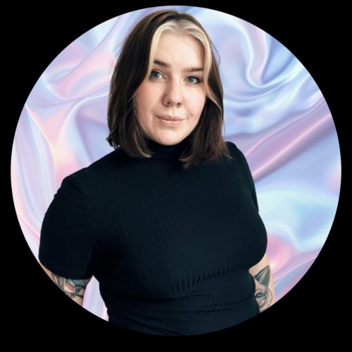 Das Bild zeigt eine Person mit mittellangem, glattem, braunem Haar, das vorne blonde Strähnen hat. Sie trägt ein schwarzes Oberteil mit einem hohen Kragen. Die Person schaut direkt in die Kamera und lächelt dezent. Der Hintergrund besteht aus einem glänzenden, pastellfarbenen Stoff, der in verschiedenen Lila-, Rosa- und Blautönen schimmert. Das Bild hat einen runden Rahmen mit schwarzem Rand.