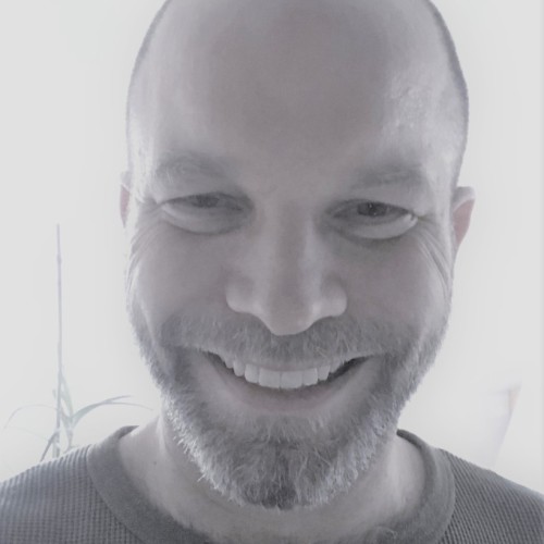 Kurzhaariger Mittvierziger mit freundlichem, optimistischem Lächeln im Gesicht. 