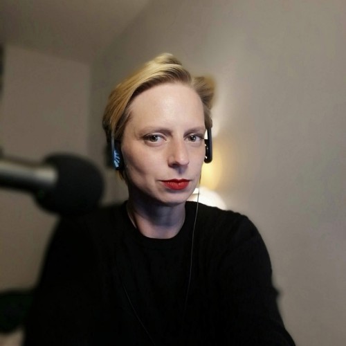 Portraitbild von Laura Hille, weißer Hintergrund und verschwommenes Mikrofon im Vordergrund