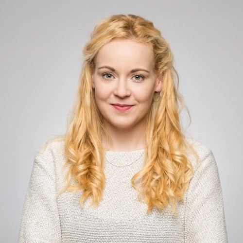 Foto von einer Frau im hellen Pullover mit blonden lockigen Haaren.