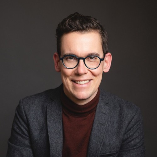 Mann mit dunklen kurzen Haaren und Brille.
