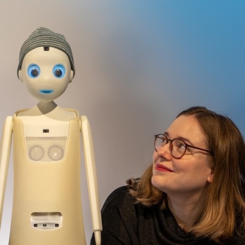 links ein roboter, rechts katharina weitz die ihn ansieht und lächelt