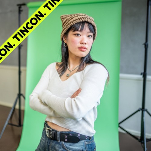 Junge Frau mit asiatischen Wurzeln steht vor einem Greenscreen