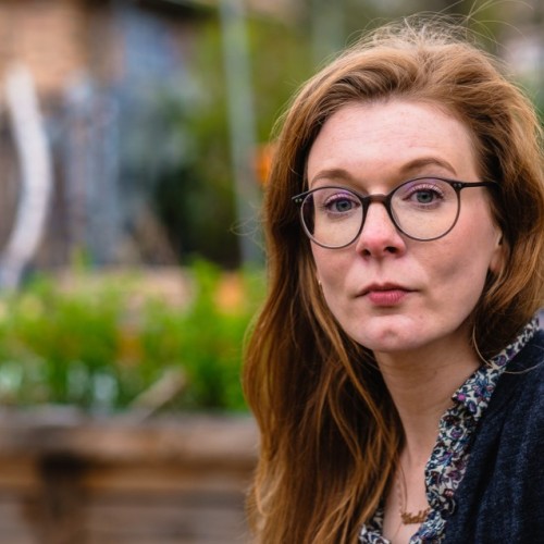 Ein Portrait von Luise Meergans, Außenaufnahme. Im Hintergrund urbaner Raum, Mauern mit Grafitti und Pflanzen.