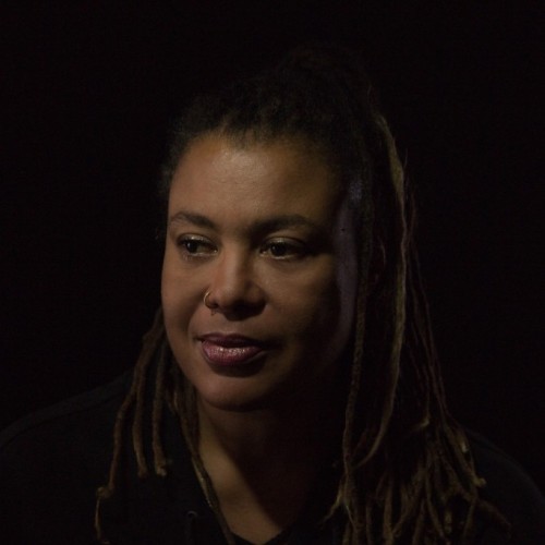 Ein Portraitbild von Nadja Ofuatey-Alazard, eine Schwarze Frau mit Dreadlocks mit Schwarzem Hintergrund.
