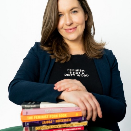 Madita Oeming lehnt auf einen Stapel Bücher rund um das Thema Porno, auf ihrem Shirt steht: Feminism is not a dirty word 