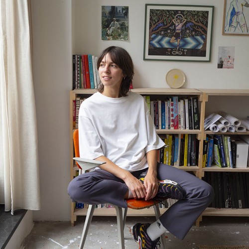 A portrait of Eva sitting on an orange chair