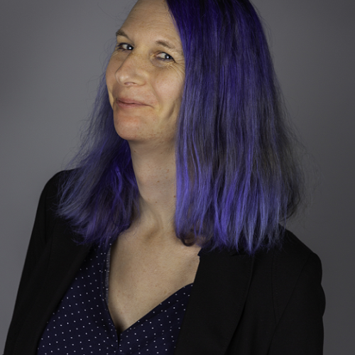 A white woman with shoulder long blue hair smiling