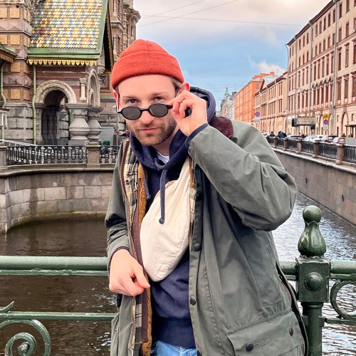 Junger Mann auf Brücke über einen Fluss vor einer Kirche in Sankt Petersburg