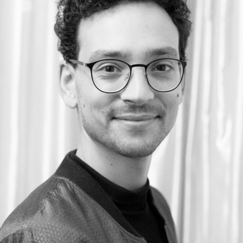 This photo shows Quincey Stumptner in a portrait, a young man with black rimmed glasses and dark hair.