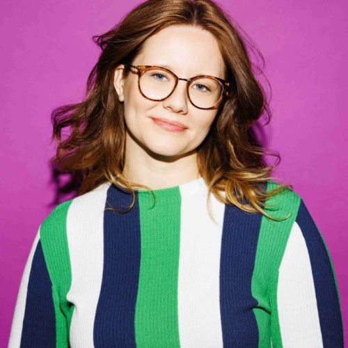 Frau mit Brille und gesteiftem Shirt vor pinkem Hintergrund