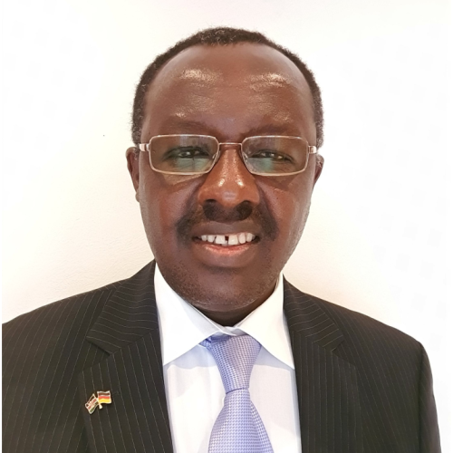 Black man in a black suit with a grey tie, smiling