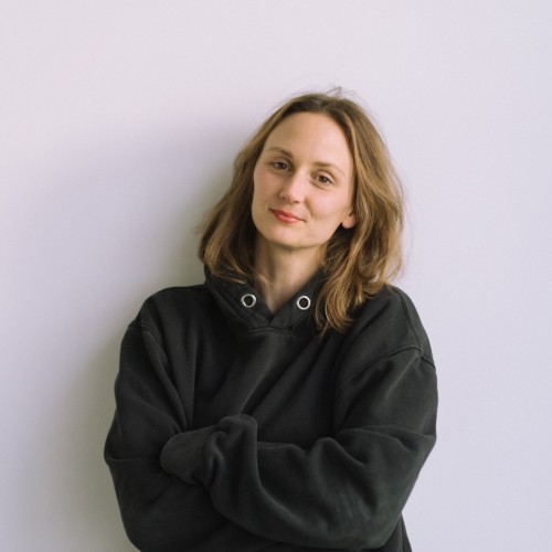 Frau mit schwarzem Pullover vor weißer Wand