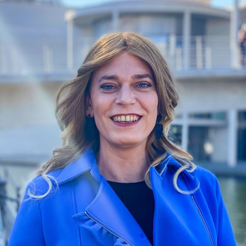 Tessa Ganserer trägt in einem leuchtend blauen Mantel und lächelt