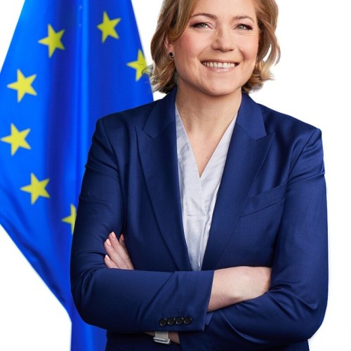 Blonde woman in front of blue EU Flag