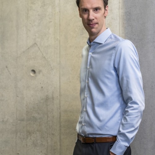 Björn Ommer im blauen Hemd vor grauer Betonwand