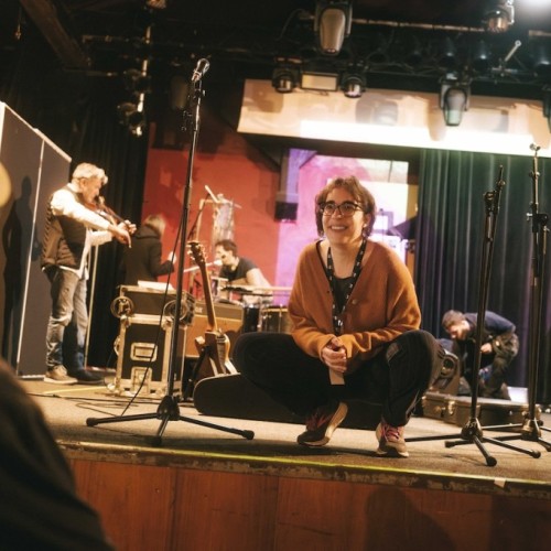 Anita on a stage with some musicians behind