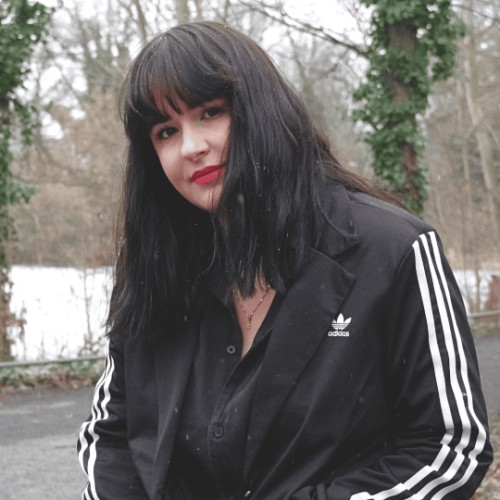 Frau mit schwarzer Adidas-Blazer und dunklen Haaren