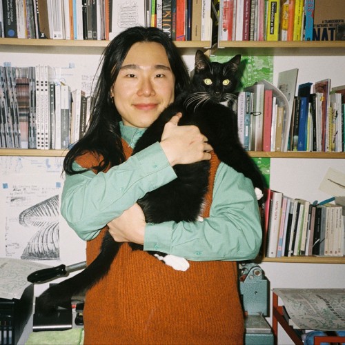 A person with long dark hair holding a black cat.