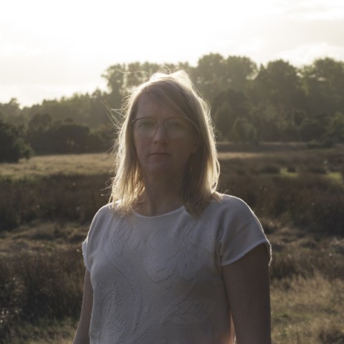 Eine Frau steht im Gegenlicht in einer Landschaft
