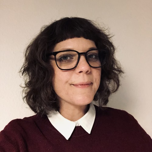 3/4 Portraitfoto einer Frau um die 40 Jahre mit Brille und schulterlangem Haar