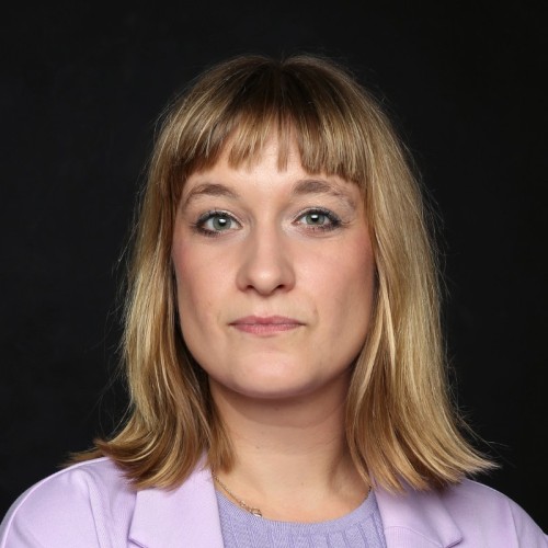 A blond woman wearing a violet jacket. 