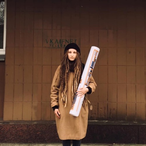 Woman in great coat and with huge rolled-up construction drawing 