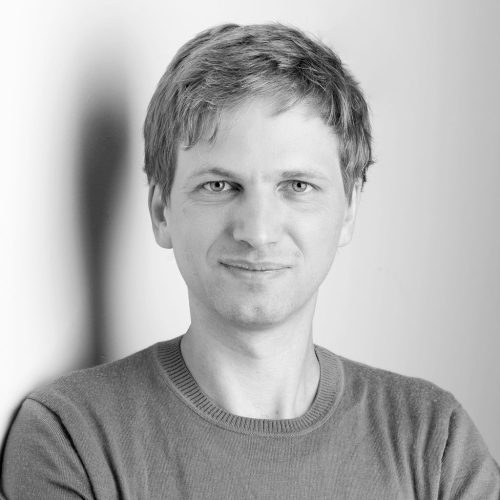 Ein Porträtfoto einer Person, die lächelt, mit neutralem Hintergrund.