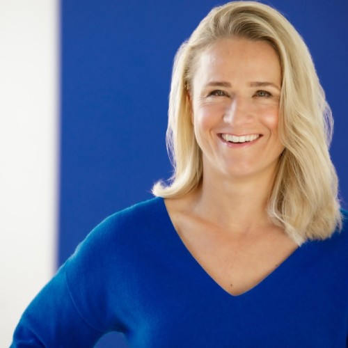 Das Bild zeigt ein Portrait von Verena Bentele. Man sieht ein lachendes Gesicht. Frau Bentele hat schulterlange blonde Haare. Sie trägt einen blauen Pullover mit V-Ausschnitt.
