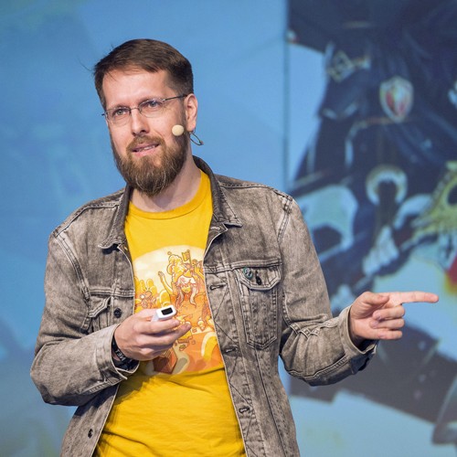 Marcus Richter steht auf einer Bühne und zeigt nach links.